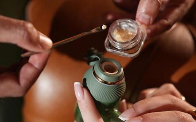 Hands preparing a premium concentrate jar with a vaporiser