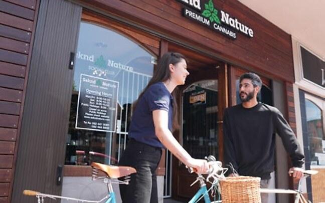 Two members with bicycles outside the Seknd Nature storefront